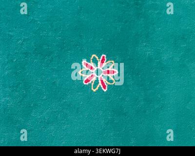 Close-up full frame view of a vibrant green textile carpet featuring a solitary, small red and yellow floral motif. Simple and elegant textured backgr Stock Photo