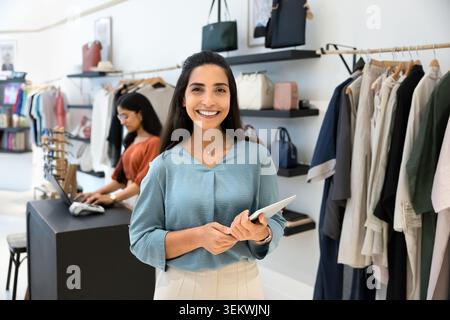 Retail manager with tablet posing in clothing store Stock Photo
