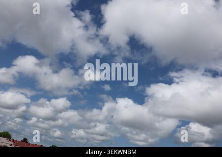 Dramatic White Clouds Floating Across Bright Blue Summer Sky. white cumulus clouds drifting across a vivid blue summer sky. Stock Photo