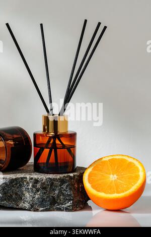 Scent diffuser beside orange on stone surface in bright light Stock Photo