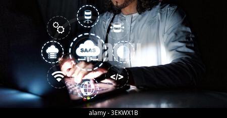 Working with Saas concepts in a dark environment while typing on a laptop Stock Photo