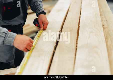 Measuring wooden planks at a furniture workshop during a weekday Stock Photo
