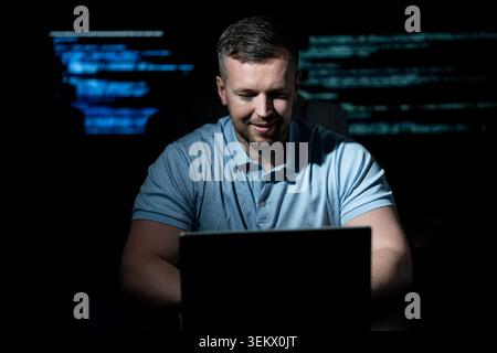 Programmer develops secure software system. Programmer writes programming on computer screen. Programmer monitors network and server logs. Programmer Stock Photo