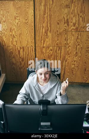 High angle view of smiling businesswoman using computer while working in tech office Stock Photo