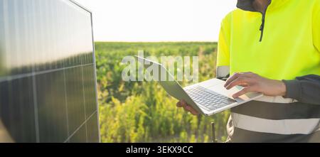 Engineer with laptop next to solar panel Stock Photo