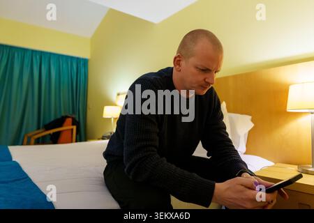 Man feeling lonely and communicating using his mobile phone while traveling Stock Photo