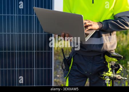 Engineer with laptop next to solar panel Stock Photo