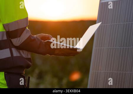 Engineer with laptop next to solar panel Stock Photo