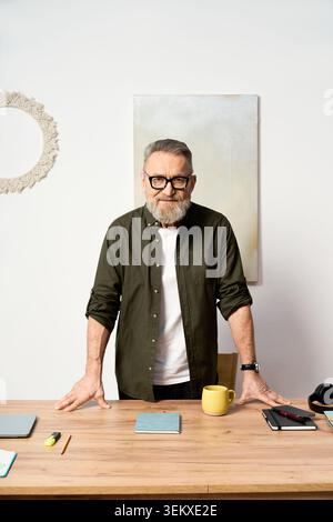 Handsome older man in glasses stands at his desk, savoring a serene day at home. Stock Photo