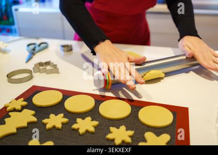 Hands rolling cookie dough with a rolling pin on a white counter Stock Photo