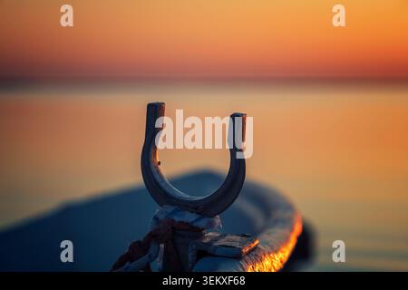 Kalajoki, Finland - 04.07.2021: Close-up of a weathered metal mooring fitting on a boat during a vibrant orange sunset over tranquil waters Stock Photo