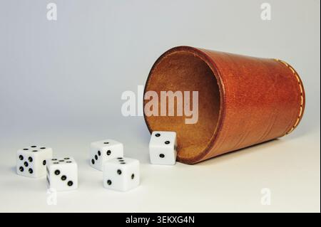 Five White Dice Spilling from Brown Leather Dice Cup on White Background Stock Photo