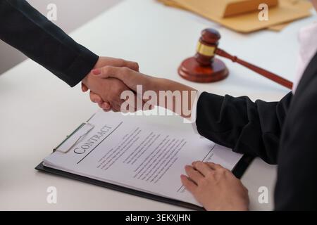 Business professionals shaking hands over signed contract Stock Photo