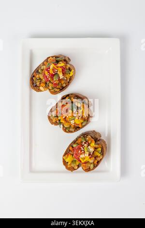 Top view flat lay of three vegetable bruschettas on white rectangular plate Stock Photo