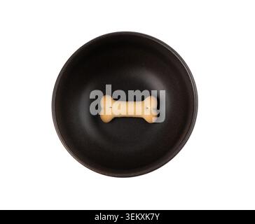 One dog biscuit in black bowl isolated, soft crunchy pet treat, single flavored small canine cookie, bone shape biscuit, puppy training food on white Stock Photo