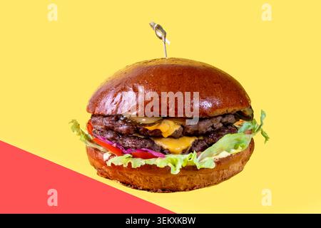Delicious burger on the board with cutlet, tomatoes and cheese, cucumber and lettuce. On a red background. Fast food. Stock Photo