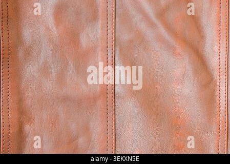 Close-up of brown genuine leather texture with vertical stitched seams. Textured brown leather background with detailed stitching, full frame. Stock Photo