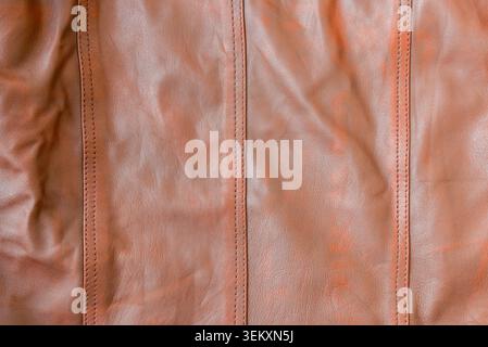 Close-up of brown genuine leather texture with vertical stitched seams. Textured brown leather background with detailed stitching, full frame. Stock Photo