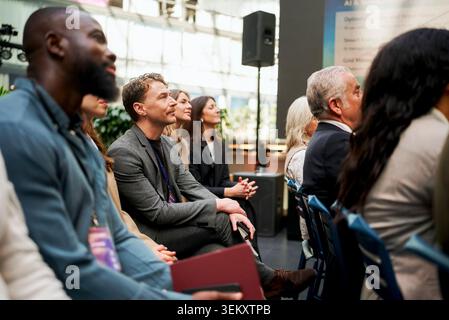 Businessman attending seminar with executives while sitting in convention hall Stock Photo
