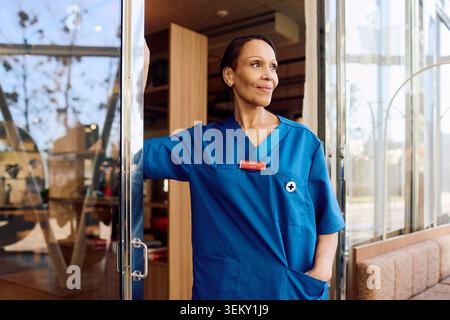 Confident senior female physician looking away while standing with hand in pocket Stock Photo