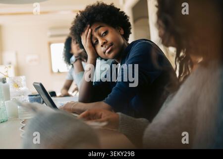 Tired boy listening to mother while sitting and studying at home Stock Photo