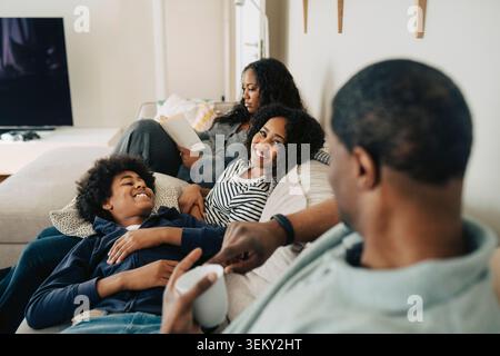 Happy children spending leisure time with father while sitting on couch at home Stock Photo