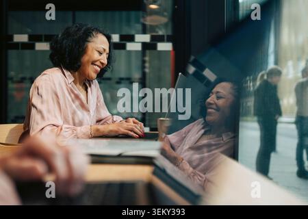 Smiling mature businesswoman working on laptop at coworking space Stock Photo