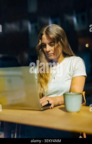 Businesswoman using laptop while working on project inside coworking space Stock Photo