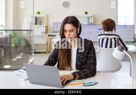 Young woman customer service operator with headset working at computer in office Stock Photo