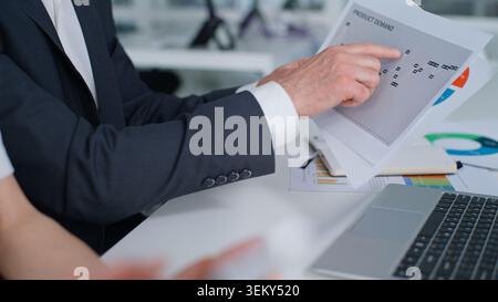 Cropped view unknown Caucasian business partners reviewing documents with stats data in office corporate meeting briefing close up unrecognizable male Stock Photo