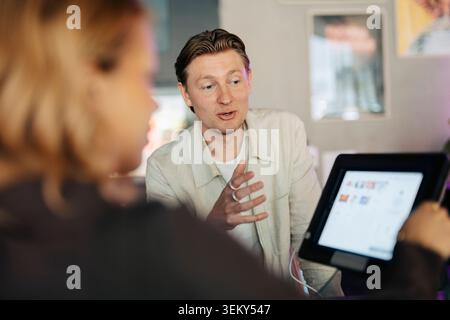 Young male receptionist explaining registration process to female guest at coworking space Stock Photo