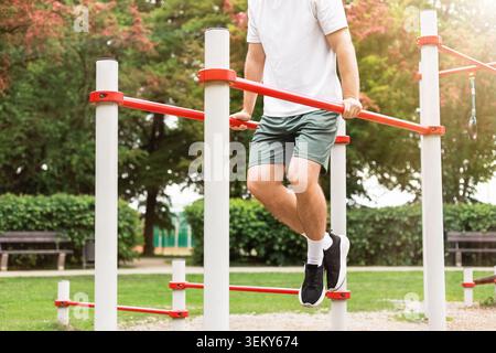Fit man doing dips on parallel bars at an outdoor sports ground. Bodyweight training, fitness, strength exercise, and active lifestyle. High quality p Stock Photo
