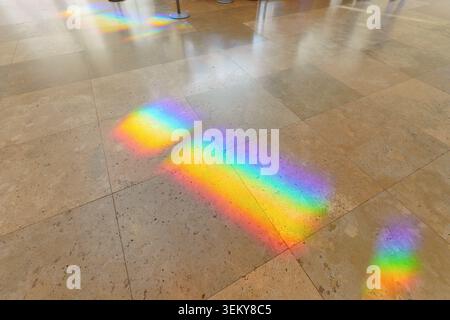 Los Angeles, California - January 8, 2026: Colorful rainbow light spectra cast brilliant reflections across the polished beige travertine tiled floor Stock Photo
