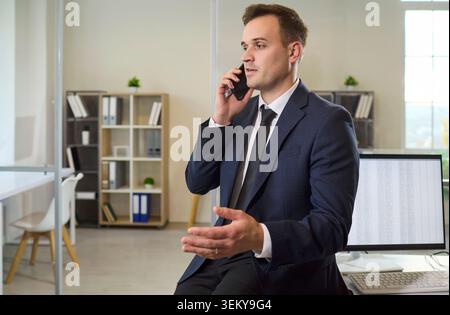 Confident businessman in suit talking on smartphone during office phone call Stock Photo