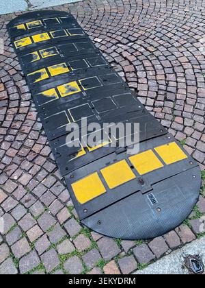 Cremona, Italy May 9th 2026 Speed bump providing traffic calming and safety, featuring black recycled rubber modules with highly visible yellow markin Stock Photo