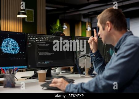 System administrator using computer in tech startup office to develop programs using AI automation. IT expert working on PC, debugging applications with artificial intelligence deep learning Stock Photo