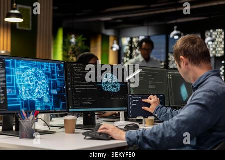 System administrator utilizing AI on PC to optimize performance and forecast issues. Tech company office worker training machine learning models to perform automatic updates Stock Photo