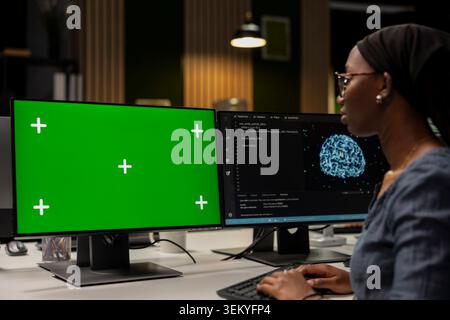 Programmer in tech startup office developing apps using AI automation on green screen PC. IT expert working on chroma key computer, debugging applications with artificial intelligence Stock Photo