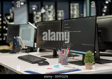 Empty startup office with PC monitors on desk to be used by programmers building scalable solutions for businesses. Computers in AI industry startup workspace leveraging machine learning technology Stock Photo