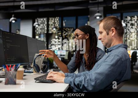 IT department staff members coding on PC in startup office, refining machine learning models to enhance automation. Woman and coworker using coding platform on computer in technology company workplace Stock Photo