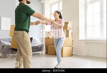 Happy couple dancing in new apartment with boxes after moving day celebration Stock Photo