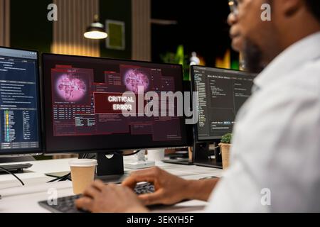 Close up of IT specialist at office desk thinking how to fix critical error alert displayed on PC screen. System administrator brainstorming how to fix computer bug affecting server network Stock Photo