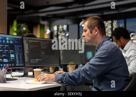 Software developer writing code, developing machine learning APIs. IT professional in tech startup working to troubleshoot software errors using artificial intelligence, resolving system crashes Stock Photo