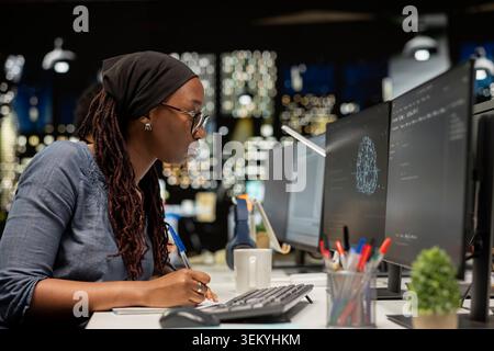 Admin writing code, developing deep learning APIs. African american woman in tech startup using PC to troubleshoot software errors using artificial intelligence, resolving system crashes Stock Photo