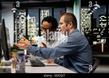 Team of programmers brainstorming in office, reviewing AI system metrics, monitoring performance dashboards. Teamworking technology company colleagues tuning neural networks using tools Stock Photo