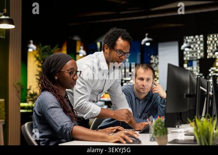 IT technicians cooperating in AI focused startup, designing, coding and debugging applications. Teamworking colleagues brainstorming, doing code testing and quality assurance Stock Photo