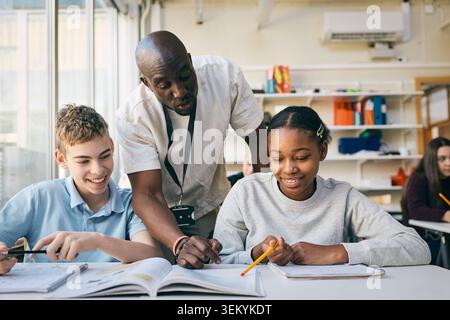 Male teacher helping students in studies at junior high school Stock Photo