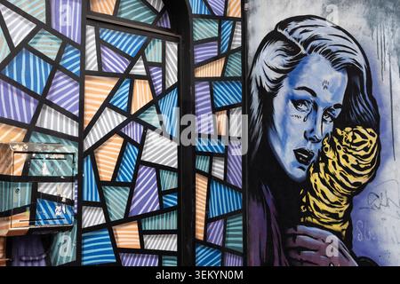 Vibrant street art installation featuring a painted geometric stained glass pattern next to a portrait mural of a woman, London Stock Photo