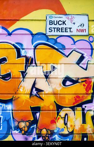 Public street art mural showing a dynamic composition of abstract yellow and orange graffiti tags painted on an urban wall on Buck Street, London Stock Photo