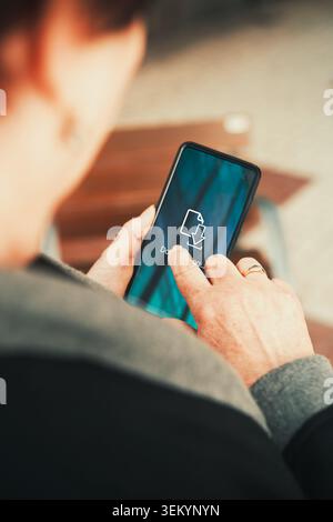 Woman Downloading Files on Smartphone over Teal Screen. File transfer, app updates, mobile data, cloud storage, and digital productivity. Stock Photo